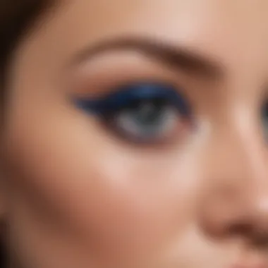 Close-up of a precision brush applying rich blue eyeliner to a model's eyelid